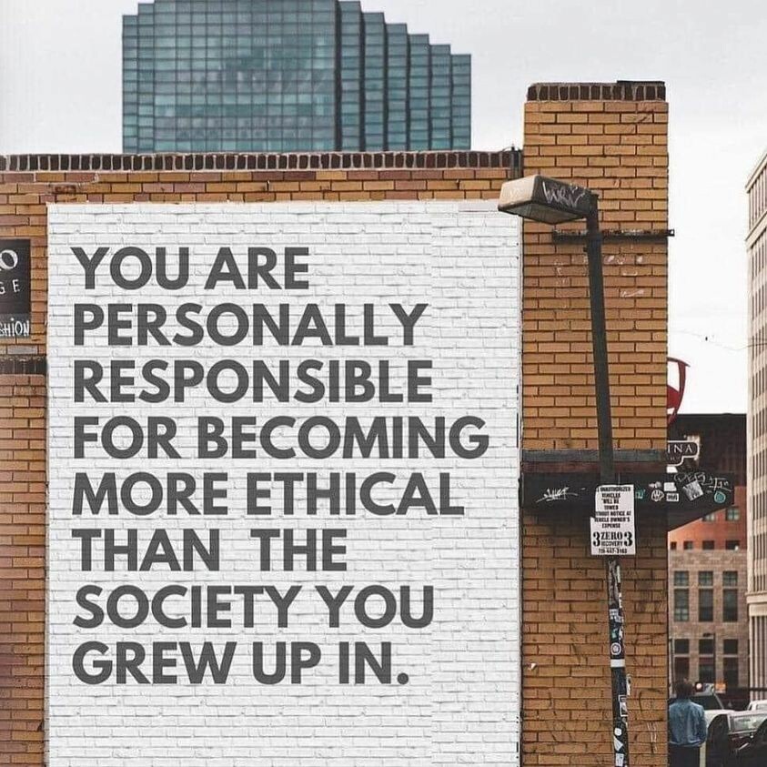 A photo of a city, a mural on the side of a bulding wall reads: "You are Personally Responsible for Becoming More Ethical Than the Society You Grew up In"